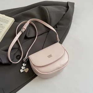 Chic pink saddle shoulder bag for women, stylish crossbody mini bag with metal heart charm.