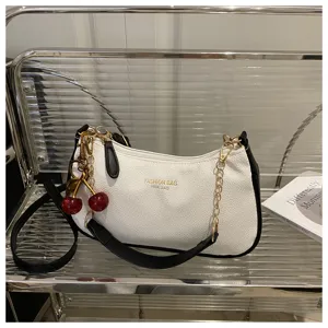 Stylish women's shoulder bag detail featuring cherry charm and gold chain strap accent.