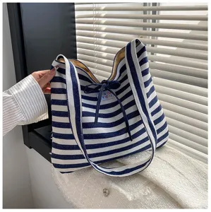 Blue and white striped shoulder bag detail showing fabric texture, sturdy handles and drawstring.