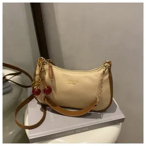 Detail view of the elegant beige hobo shoulder bag with brown trim and cute cherry charm accessory.