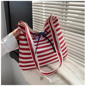 Close-up view of stylish red and white striped canvas shoulder tote bag with bow detail.