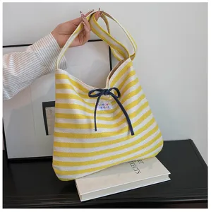 Close-up detail of the yellow and white striped hobo shoulder bag with a dark blue bow drawstring.