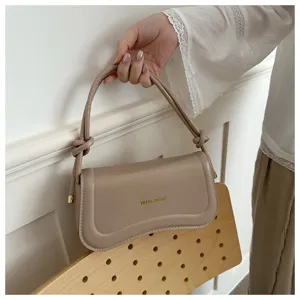Minimalist beige shoulder bag detail view, chic knotted handle and stylish curved flap design.