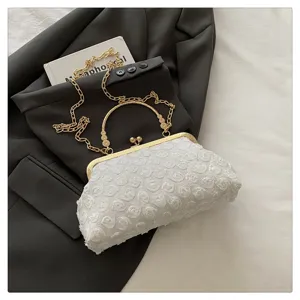 Detailed view of elegant white rose lace evening clutch bag with a gold metal frame and chain.