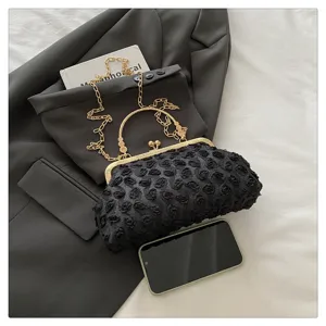 Exquisite black rose textured evening bag with gold metal frame and chain strap detail view.