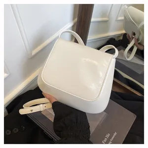 Detailed view of a white leather saddle bag with adjustable strap for women. Elegant retro design.
