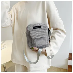 Detailed shot of a stylish grey corduroy crossbody bag with flap pocket and comfortable strap.