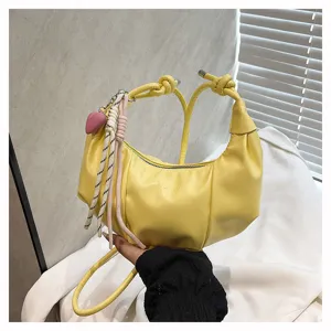 Detailed view of yellow hobo underarm bag with cute heart charm and braided rope hanging.