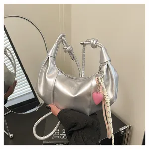 Silver underarm shoulder bag detail showing metallic texture, pleated design and heart charm.