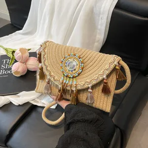 Handmade woven straw shoulder bag with ethnic tassel and beaded medallion for summer beach.