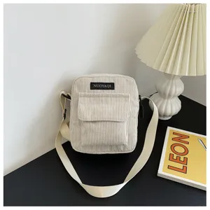 Corduroy crossbody bag detail view showing texture and strap detail in minimalist setting.