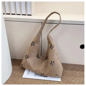 Detailed view of the casual suede tote bag featuring delicate cut-out floral patterns.
