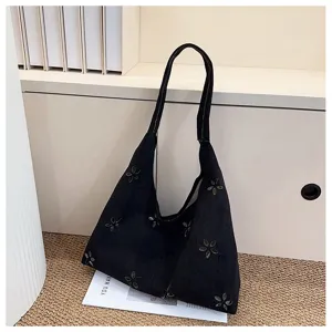 Detailed view of black frosted tote bag with floral studs, casual daily shoulder handbag.