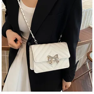 White quilted crossbody chain bag with silver bow detail, elegant shoulder bag for women.