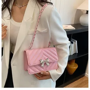 Pink quilted chain shoulder bag detail with metallic bow and elegant fashion design style.