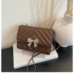 Elegant brown quilted shoulder bag with silver bow accent and chain strap for women.