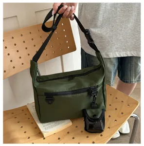 Detail shot of dark green nylon messenger bag showing multi-pocket design and removable mini pouch.