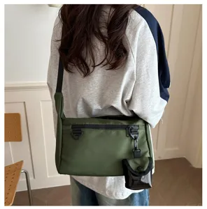 Detail view of the green messenger bag worn on back, showing adjustable strap and small pouch.
