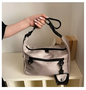 Close-up detail of casual nylon shoulder bag featuring dual zipper pockets and strap.