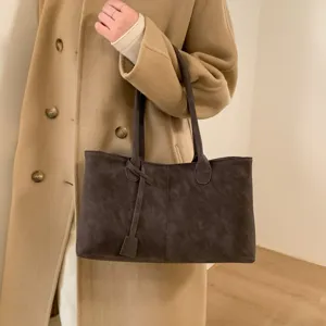 Detalle del bolso tote de ante marrón oscuro, con asas dobles y elegante cinta lateral elegante.