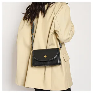 Stylish black leather crossbody bag for women with gold flower clasp and patterned strap.