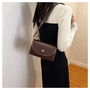 Detailed view of the women's retro brown leather crossbody bag with ethnic strap and charm.