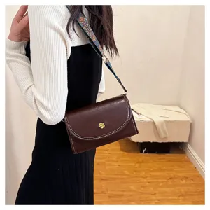Vintage brown leather crossbody bag detail with unique flower metal lock and wide strap.