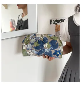 Detail van de met bloemen en pailletten geborduurde clutch, prachtig vakmanschap en een uniek design.