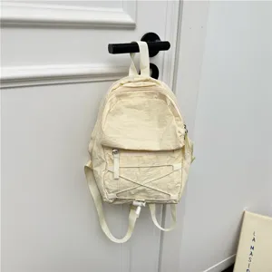 Mini beige nylon backpack with front pocket and bungee cord, casual lightweight school bag.