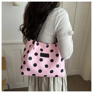 Vista dettagliata della borsa tote in tela a pois rosa e neri, stile borsa a spalla casual.