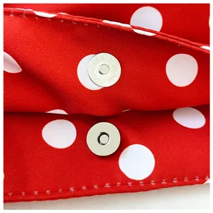 Close-up detail of the red polka dot nylon fabric bag with metal magnetic snap closure.