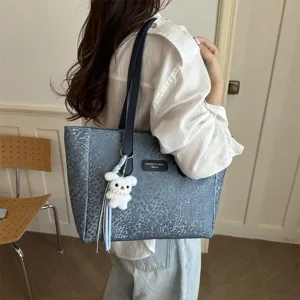 Detail du sac cabas bleu avec pendentif en peluche et bandouliere pour le travail quotidien.