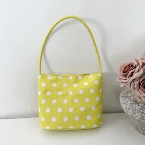 Yellow polka dot nylon underarm bag detail, compact shoulder handbag for daily commute.