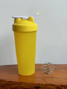 Detail view of yellow fitness shaker bottle with stainless steel mixing ball for protein.