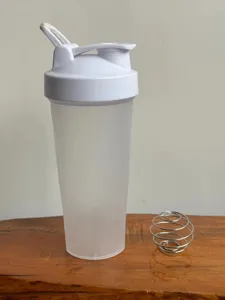 Detailed view of frosted protein shaker bottle with white leakproof lid and metal whisk ball.