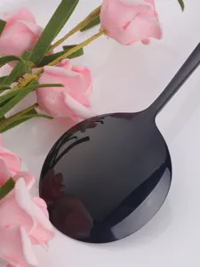 Close-up detail of black stainless steel dining spoon with pink artificial rose flower decor.