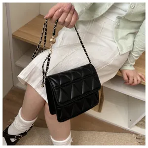 Detailed shot of a stylish black quilted cross body bag with gold chain strap and chic design.