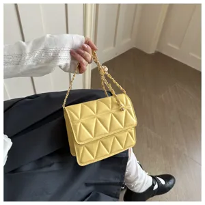 Detailed view of yellow quilted chain shoulder bag, trendy crossbody handbag accessory.