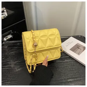 Detailed close-up of yellow quilted shoulder bag featuring stylish chain strap & hardware.