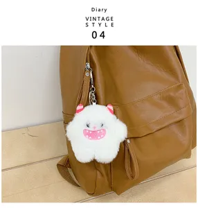 Vue détaillée du sac à dos vintage en cuir marron avec charm porte-clés monstre en peluche.