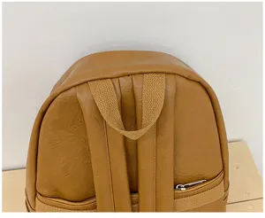 Gros plan sur le haut et les bretelles du sac à dos en cuir marron vintage, détails fins.