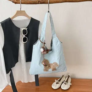 Élégant cabas en toile bleue avec charmant pendentif de cheval, sac porté épaule chic quotidien.
