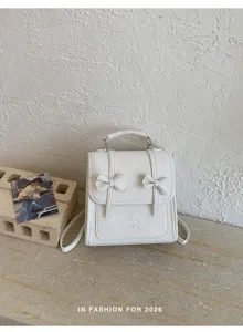 Vista dettagliata del mini zaino bianco con graziosi fiocchi doppi e pratico manico.