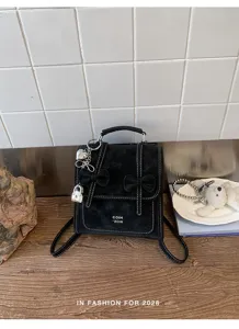 Primo piano dettagliato dello zaino nero in camoscio con fiocchi e lucchetto metallico.