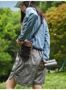 Outdoor chest bag detail view in nature, featuring contrast plaid pattern and bungee cord design.