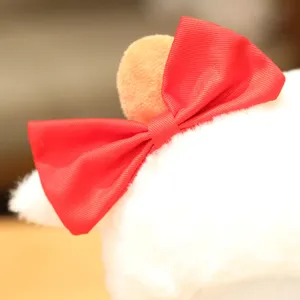 Close-up detail of cute white plush sheep toy with a vibrant red bow, soft and fluffy texture.