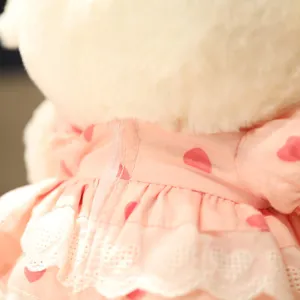 Cute plush sheep doll dress detail close-up, soft fabric toy with pink heart pattern.