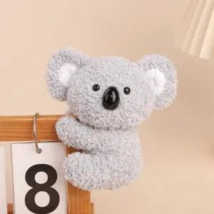 Cute grey koala plush clip toy hanging on wooden calendar, soft companion doll for office desk.