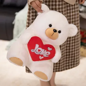 Cute white plush teddy bear holding a red heart with love embroidery, soft stuffed toy gift.