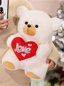 White plush teddy bear holding red heart love pillow, soft stuffed toy for holiday gift.